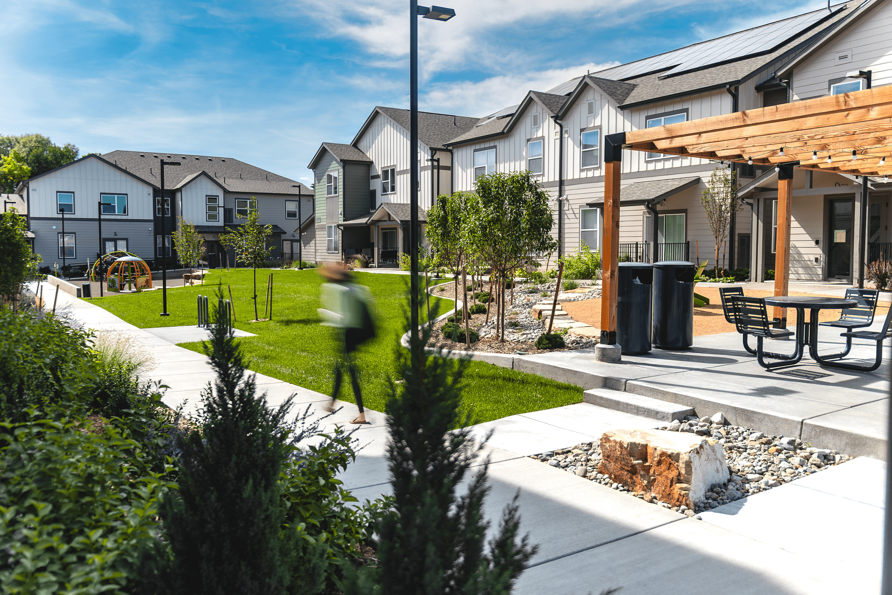 A person is walking in a park with houses in the background.